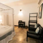 Deluxe Pool View Room with canopy bed and seating corner
