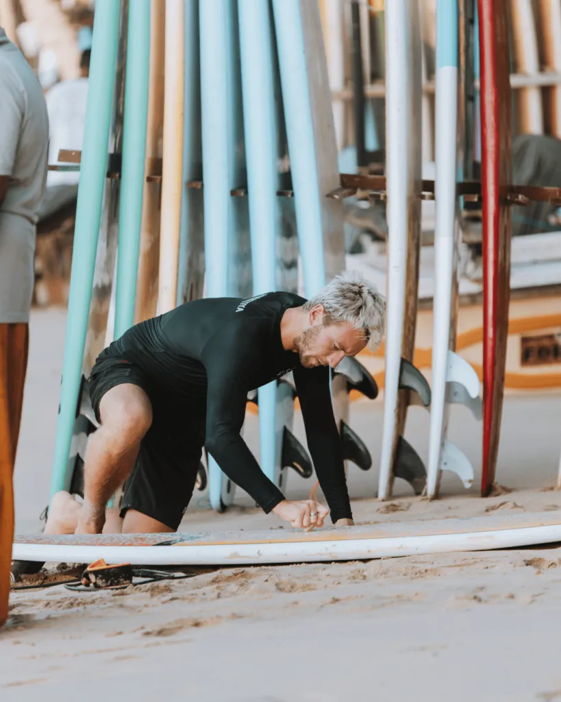 Guest waxing a surfboard at the Jasper House surf rack