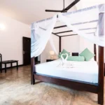 Deluxe Standard Room with netted four-poster bed and green accent cushions