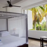 Deluxe Open Air Room with white bedding and palm tree outlook