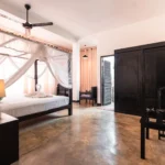 Deluxe Standard Room with canopy bed, wardrobe and polished concrete floor